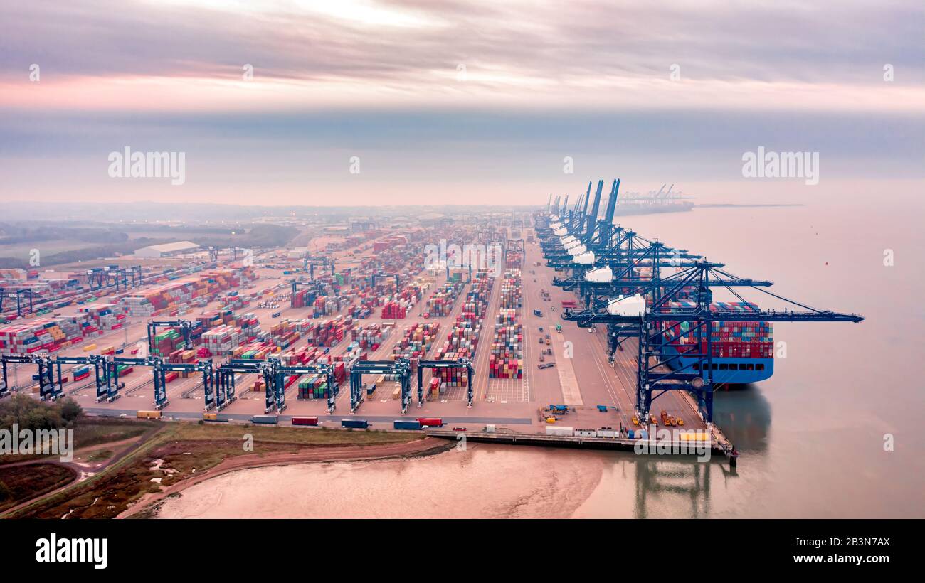 Aerial photograph of rows of stacked shipping containers and loading gantrys viewed hazily through the early morning mist. Stock Photo