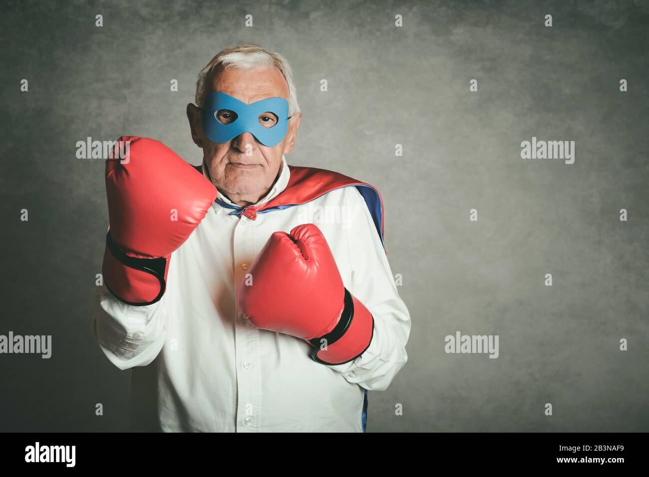 Super grandpa, senior man dressed as a superhero on gray background Stock Photo