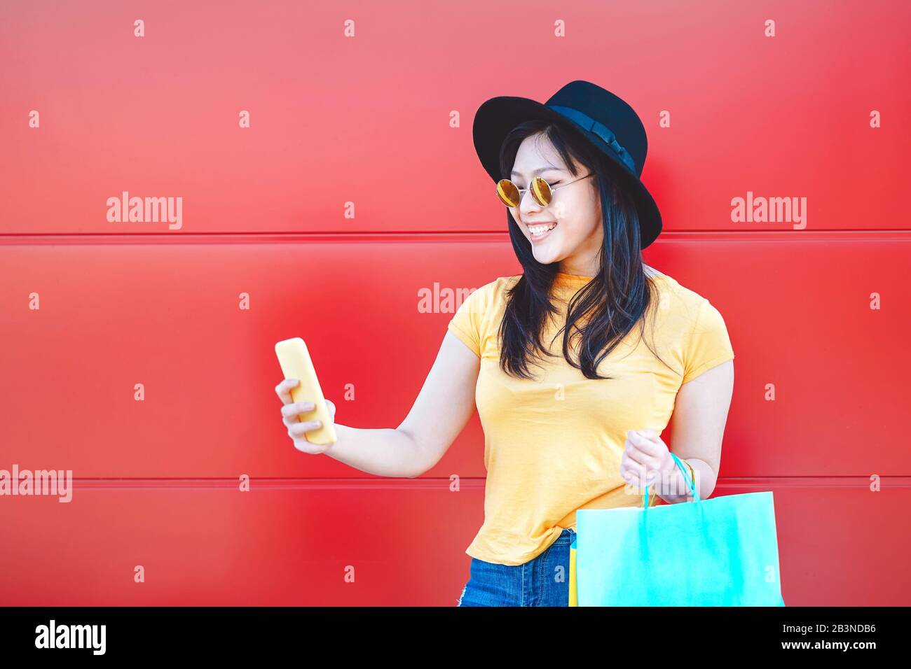 Asian fashion girl doing shopping in mall center using mobile smartphone - Happy Chinese woman having fun buying new clothes in vacation Stock Photo