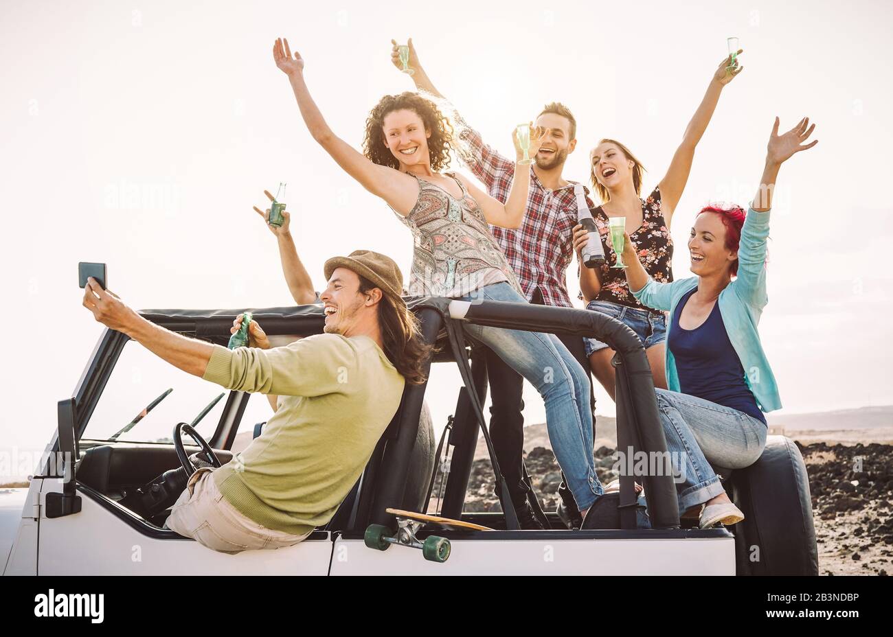 Happy friends taking selfie with mobile smart phone on convertible car - Millennial young people having fun making party during their road trip Stock Photo