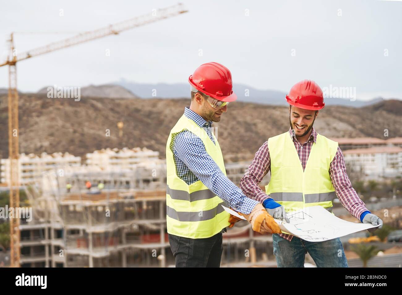 Work engineers discussing about new building area - Young builders reading the project in the construction site Stock Photo