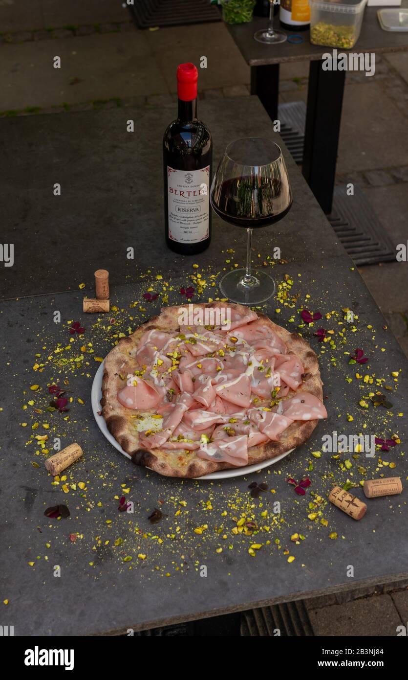 Rustic mortadella topped pizza with red wine at Italian restaurant