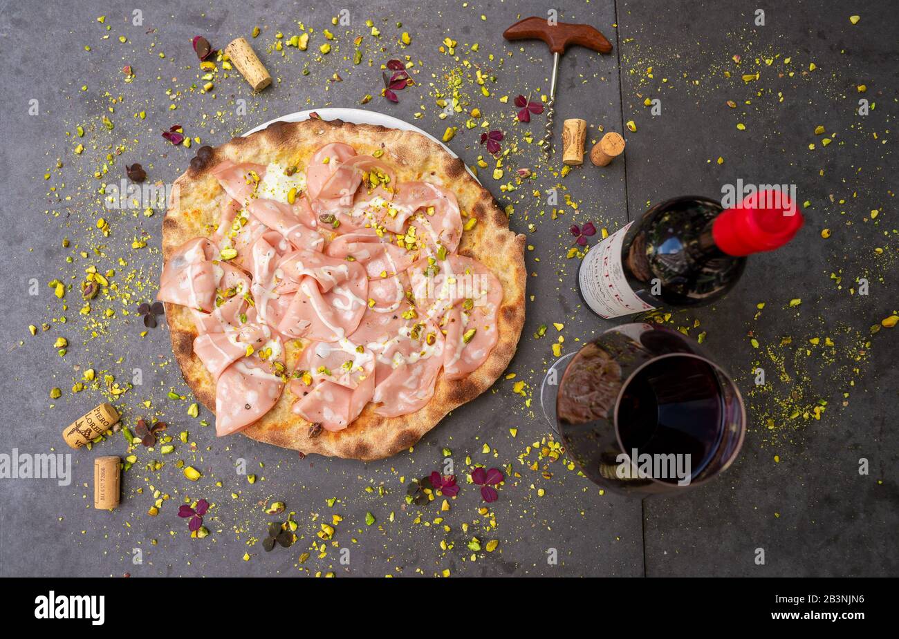 Rustic mortadella topped pizza with red wine at Italian restaurant