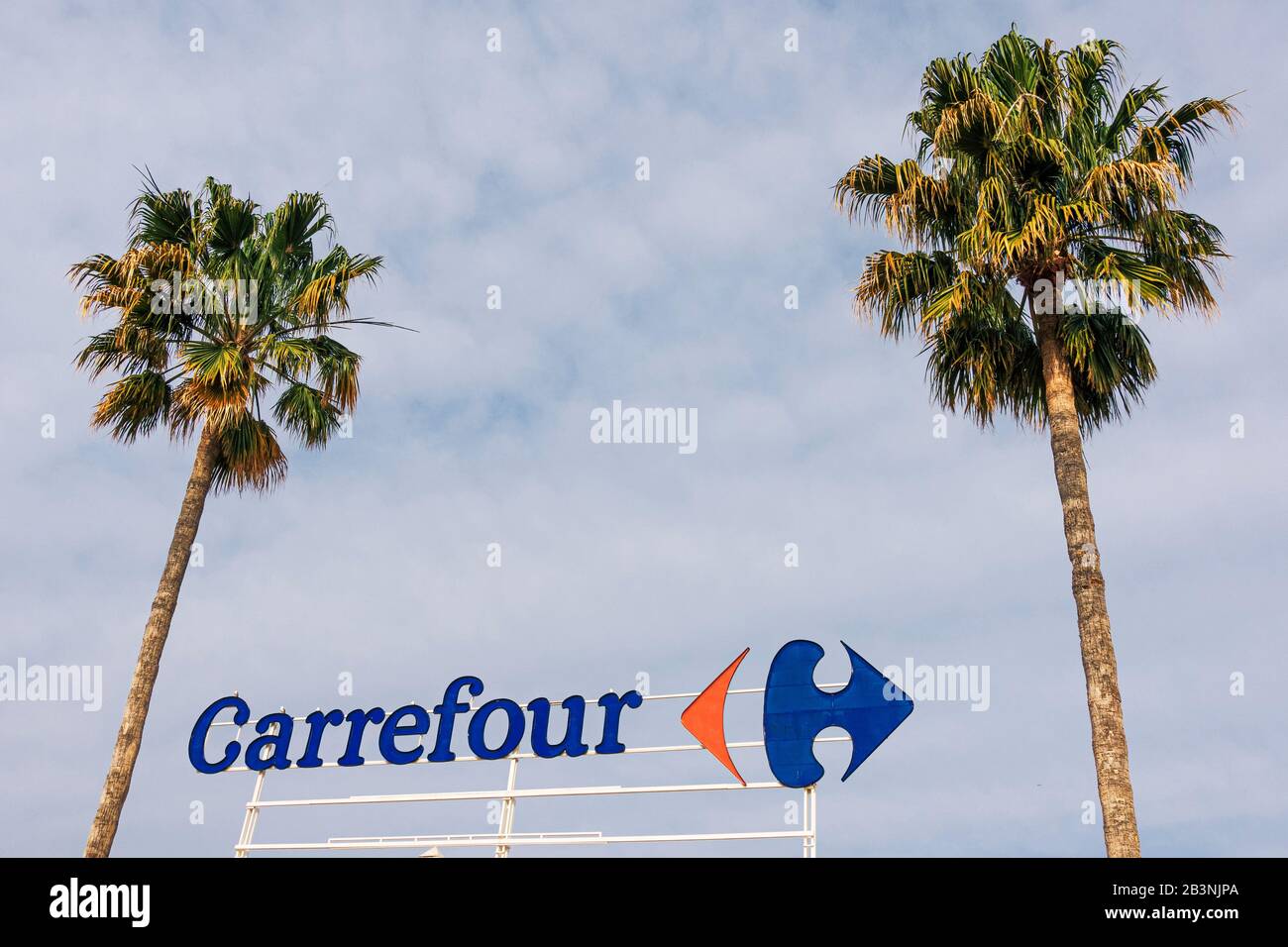 Finestrat, Spain - March 5, 2020: Carrefour logo on Carrefour supermarket with blue sky and palms background Stock Photo