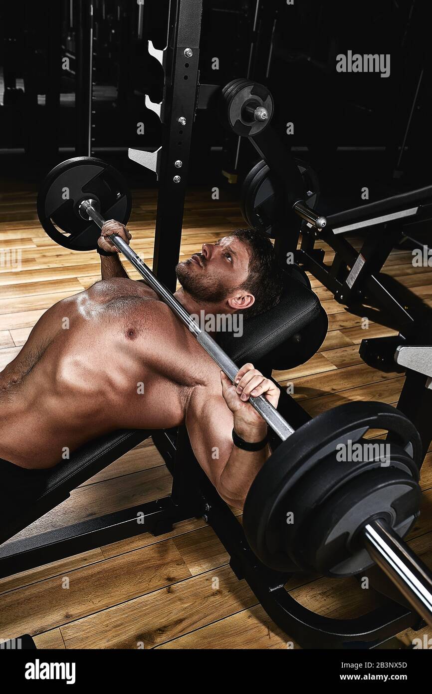 Young muscular man lifting a barbell bench press in the gym. Beautiful  body, goal achievement, Sport as a way of life Stock Photo - Alamy