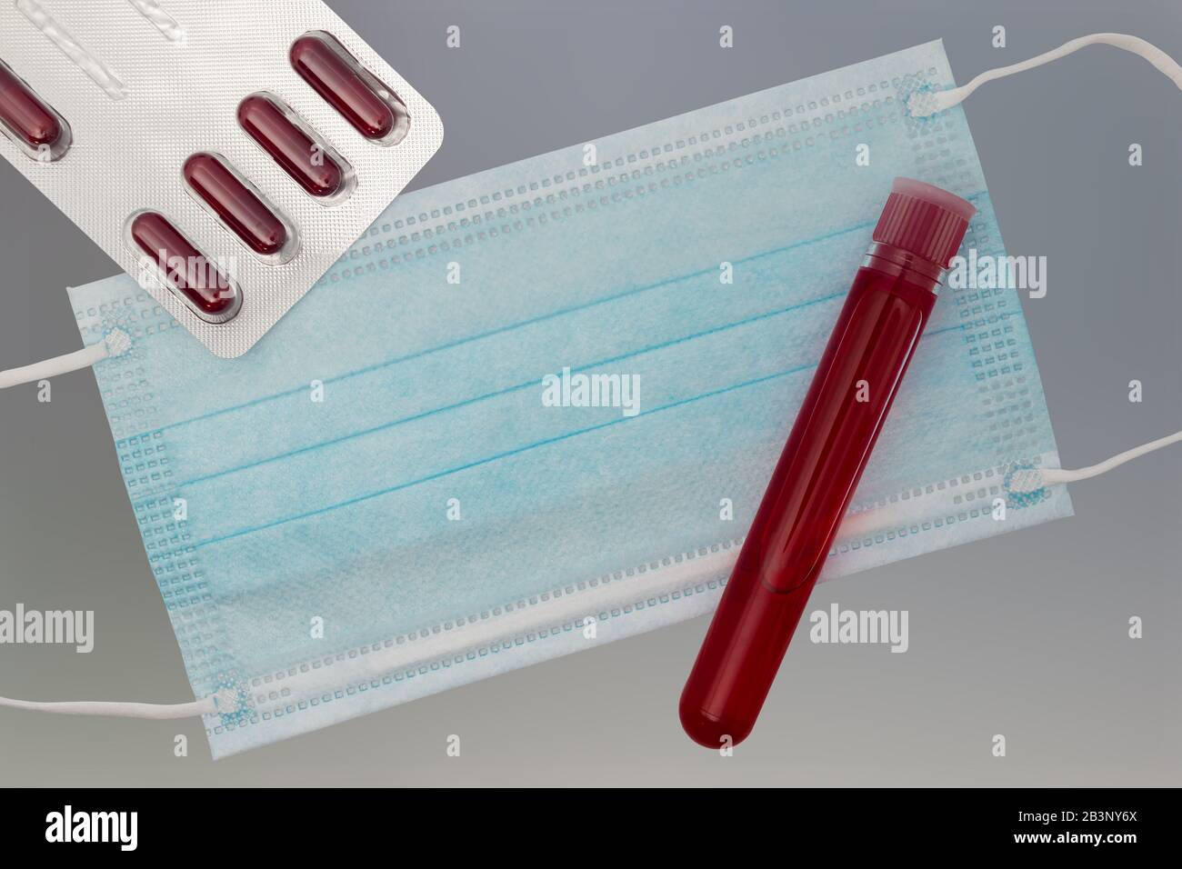 Top view of desk in laboratory with pills, test tube with blood and respiratory mask Stock Photo