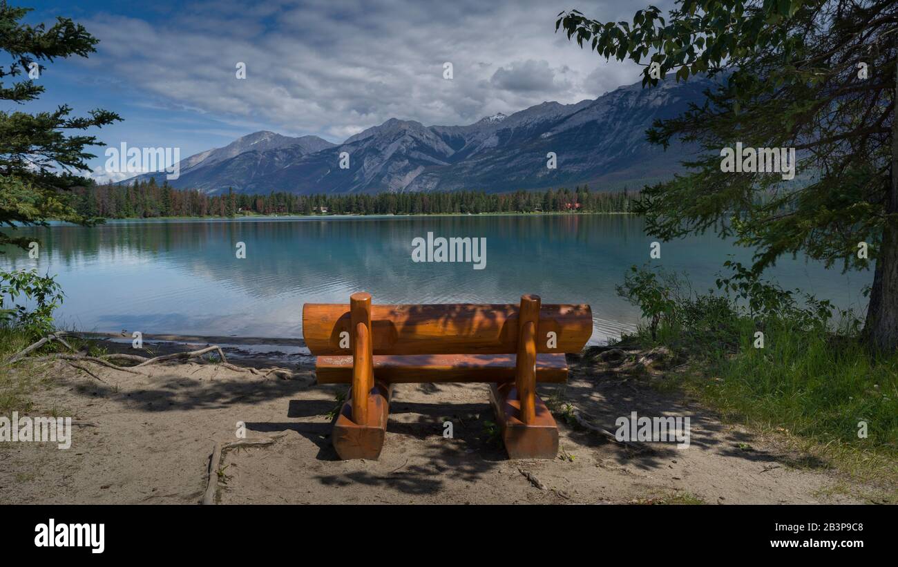 Log bench at the lakeside with mountain range in the background, Edith ...