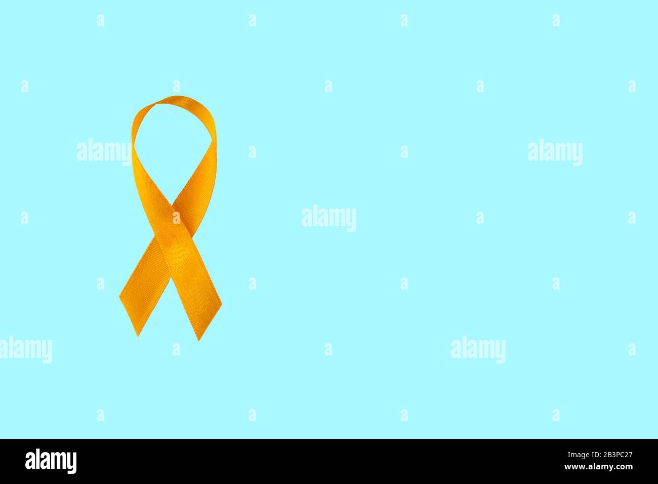 Childhood Cancer Awareness Yellow Ribbon on blue background with copy space.  Stock Photo