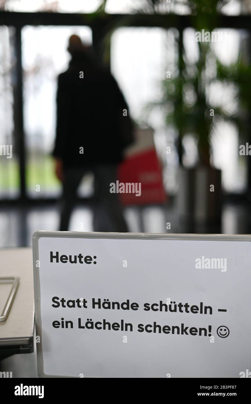 dpatop - 05 March 2020, Berlin: A sign with the inscription 'Heute statt Hände schütteln - ein Lächeln schenken' (Today instead of shaking hands - give a smile) is located in the entrance area for the event Medientage Mitteldeutschland. This is intended as a precautionary measure because of the corona virus currently in circulation. The event will precede the main Leipzig congress in May. Photo: Frank May/dpa - Zentralbild/dpa Stock Photo