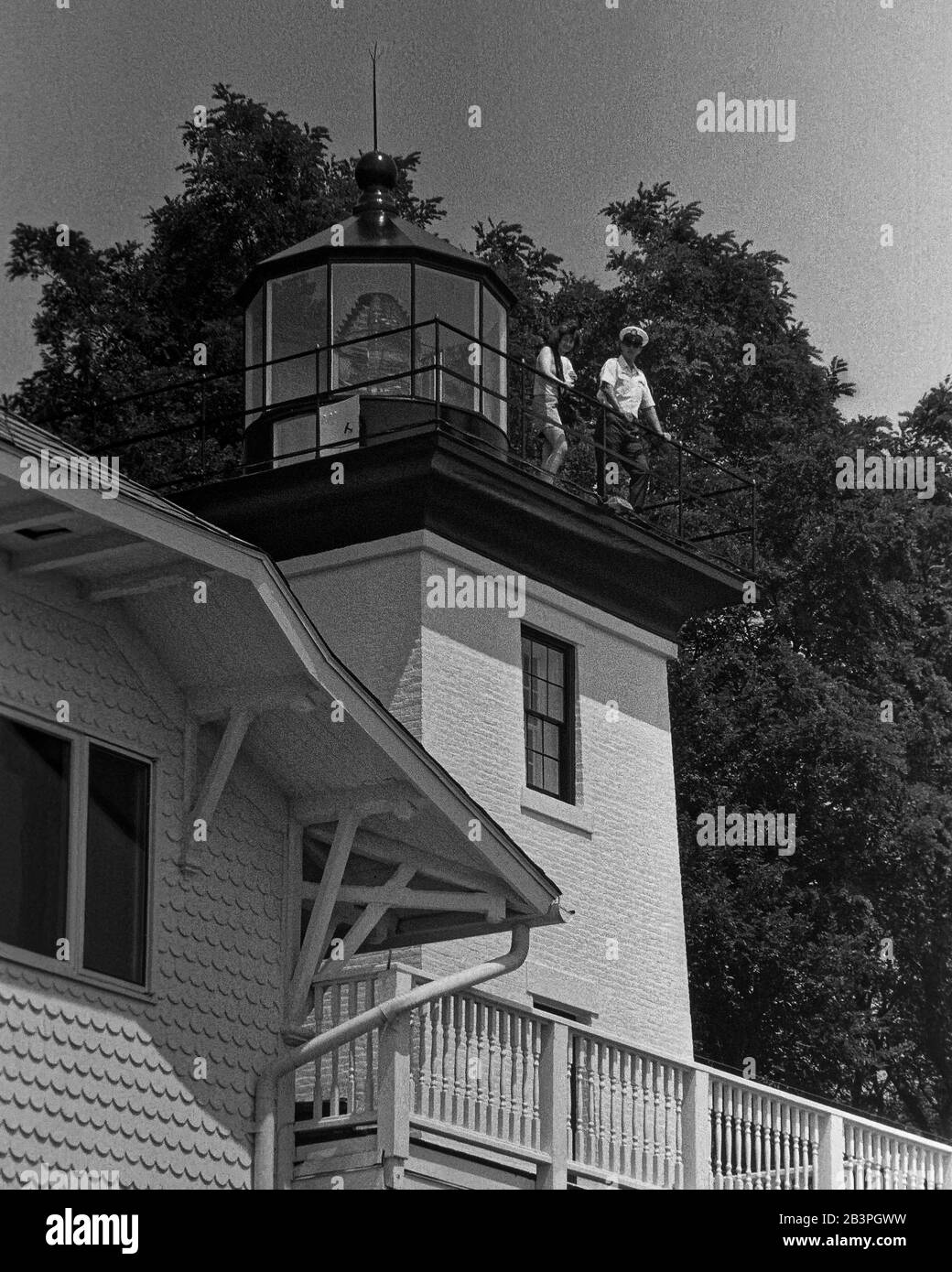 Historic Hospital Point lighthouse tower glistens in the morning sunlight with a visitor and coastguard caretaker perched on the rooftop balcony. Stock Photo
