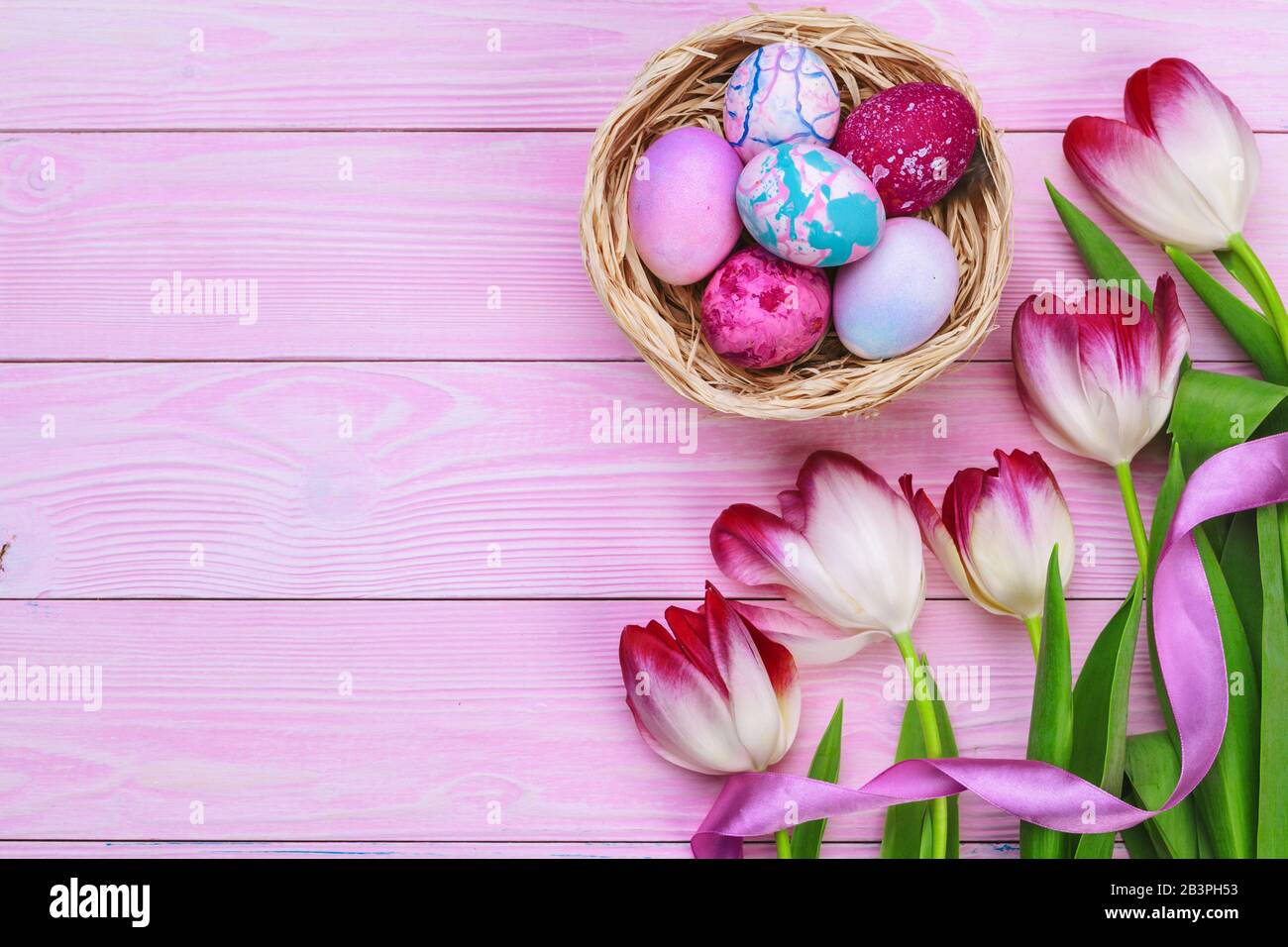 Easter background with colorful eggs and tulips over pink wood. Top ...