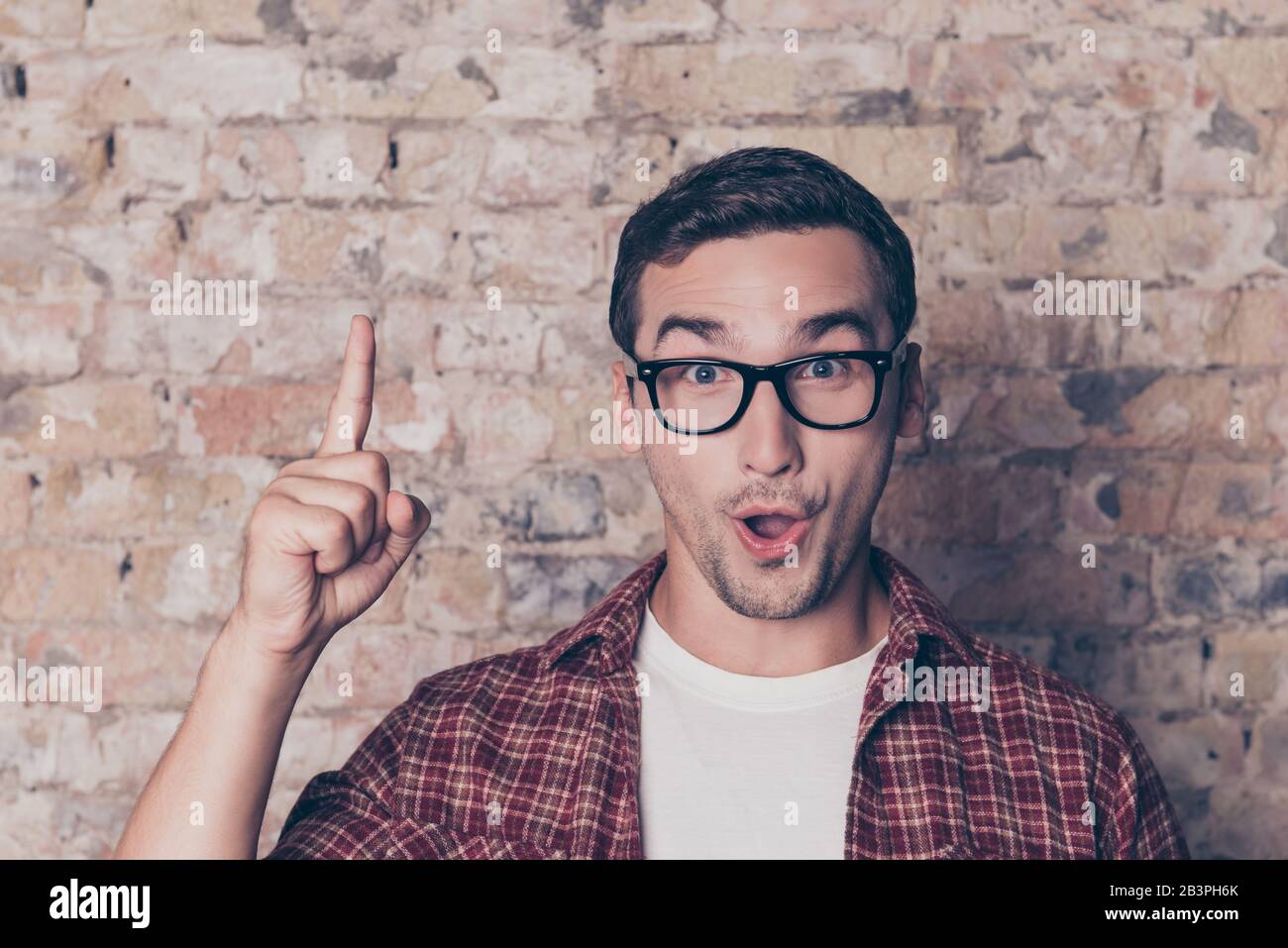 Happy young nerd guy raising his finger having an idea Stock Photo - Alamy