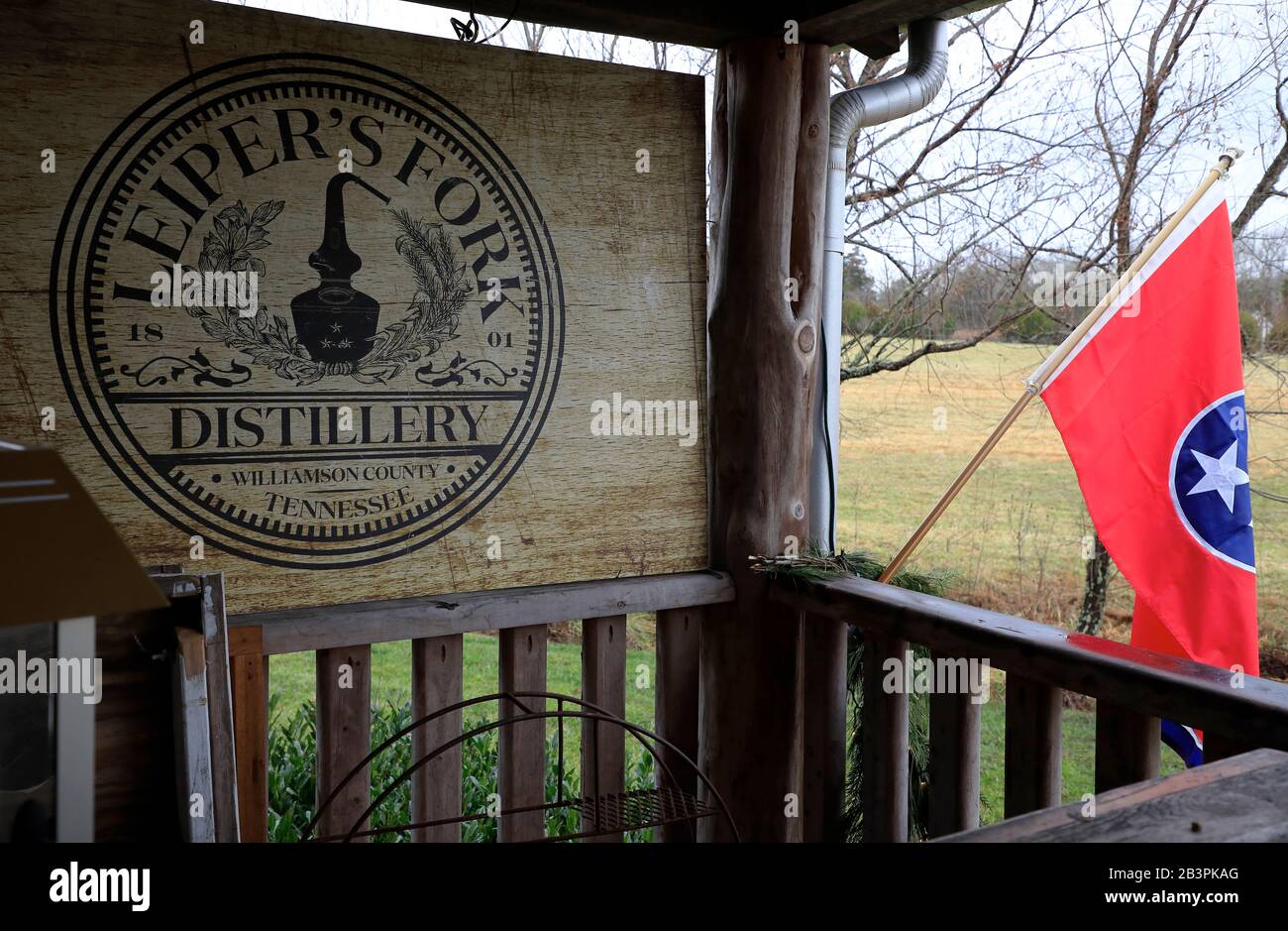 The wooden sign of Leiper's Fork Distillery on the porch of historic log home of Leiper's Fork Distillery with the state flage of Tennessee.Franklin.Tennessee.USA Stock Photo