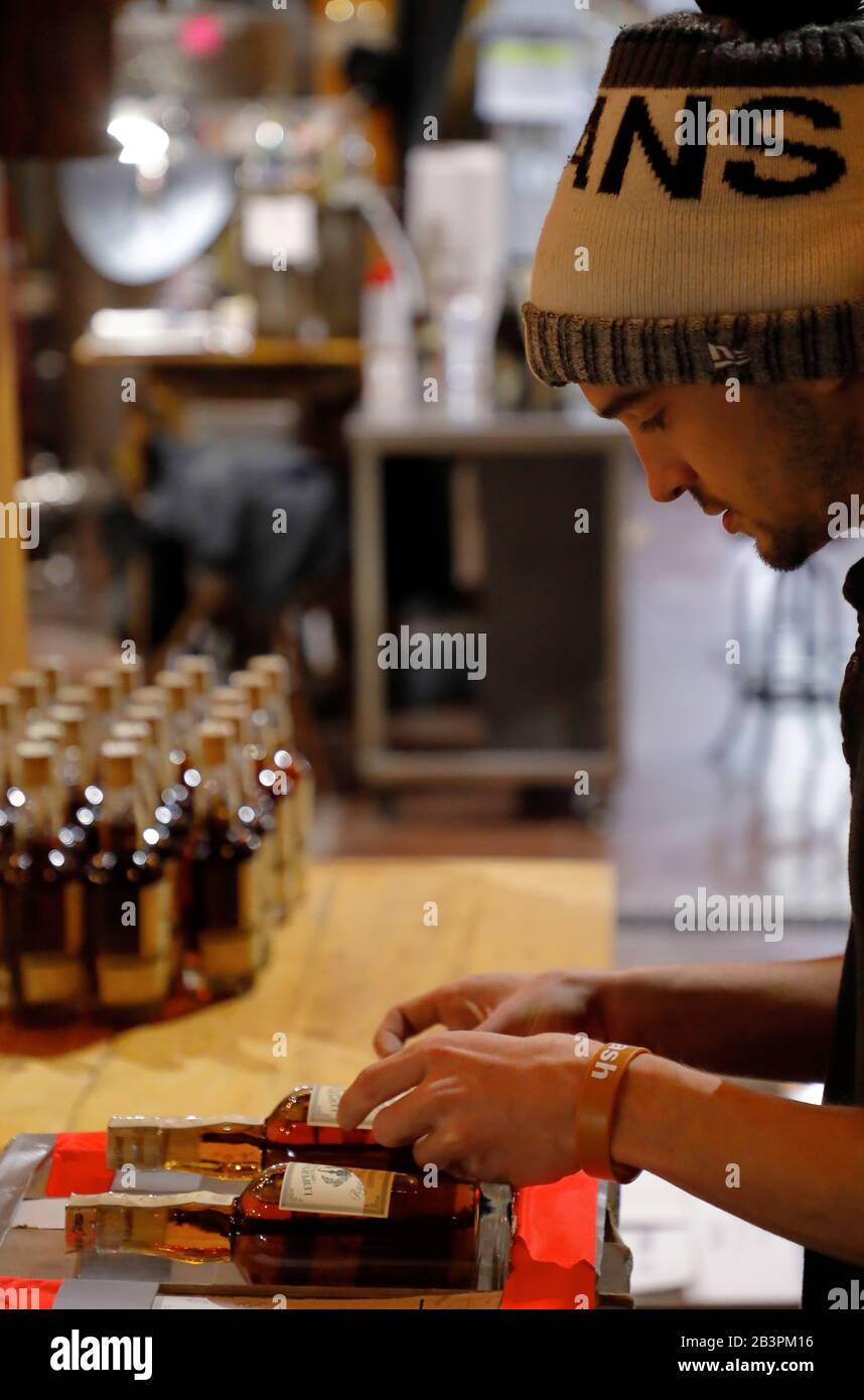 A worker hand labeling whiskey bottle inside Leiper's Fork Distillery.Franklin.Tennessee.USA Stock Photo