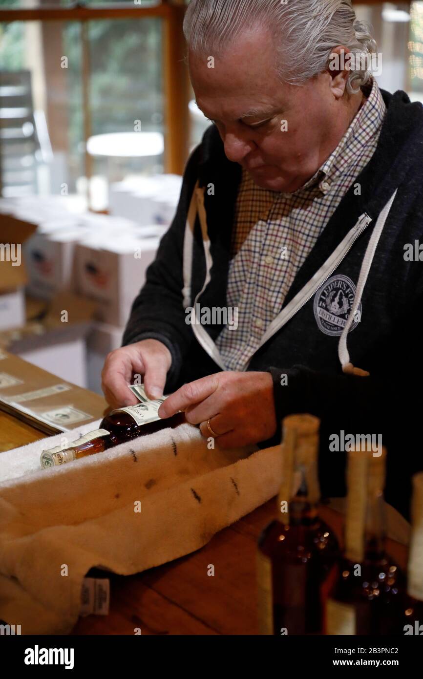 A male worker hand labeling whiskey bottle inside Leiper's Fork Distillery.Franklin.Tennessee.USA Stock Photo
