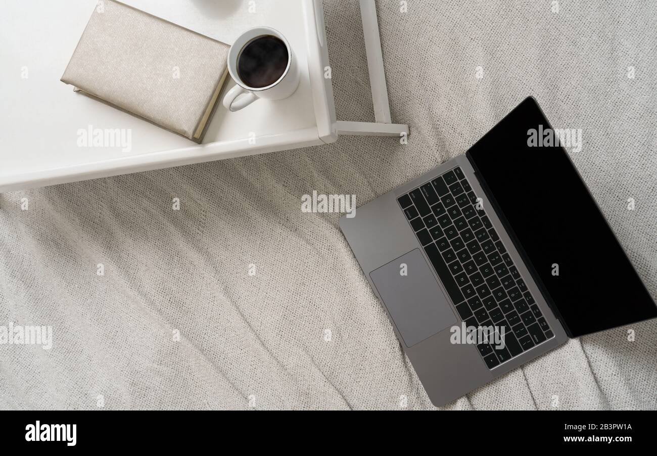 Top view of coffee cup and book on bed table and Laptop on the bed ...