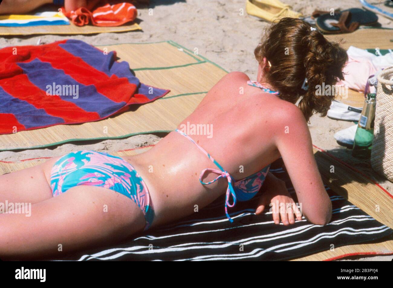 South Padre Island Texas USA, circa 1990: Female college student gets sunburned while sunbathing during spring break. ©Bob Daemmrich Stock Photo