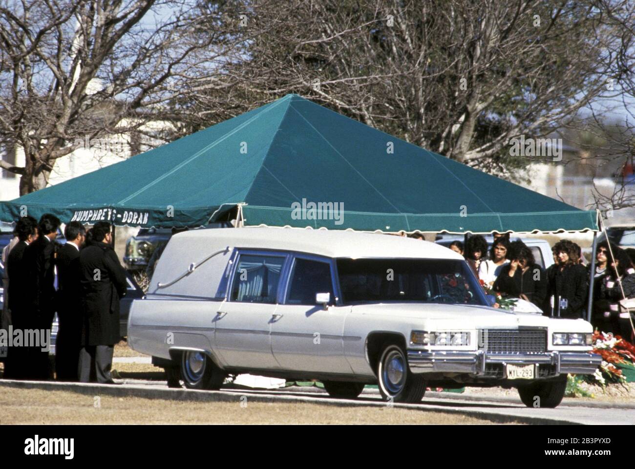 Del Rio Texas USA (undated): Mourners gather around gravesite in cemetery as white hearse bears basket of the deceased at South Texas funeral. ©Bob Daemmrich Stock Photo