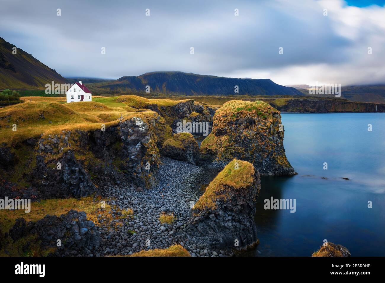 Sea shore in Iceland with cliffs and a small house in the village of Arnarstapi Stock Photo