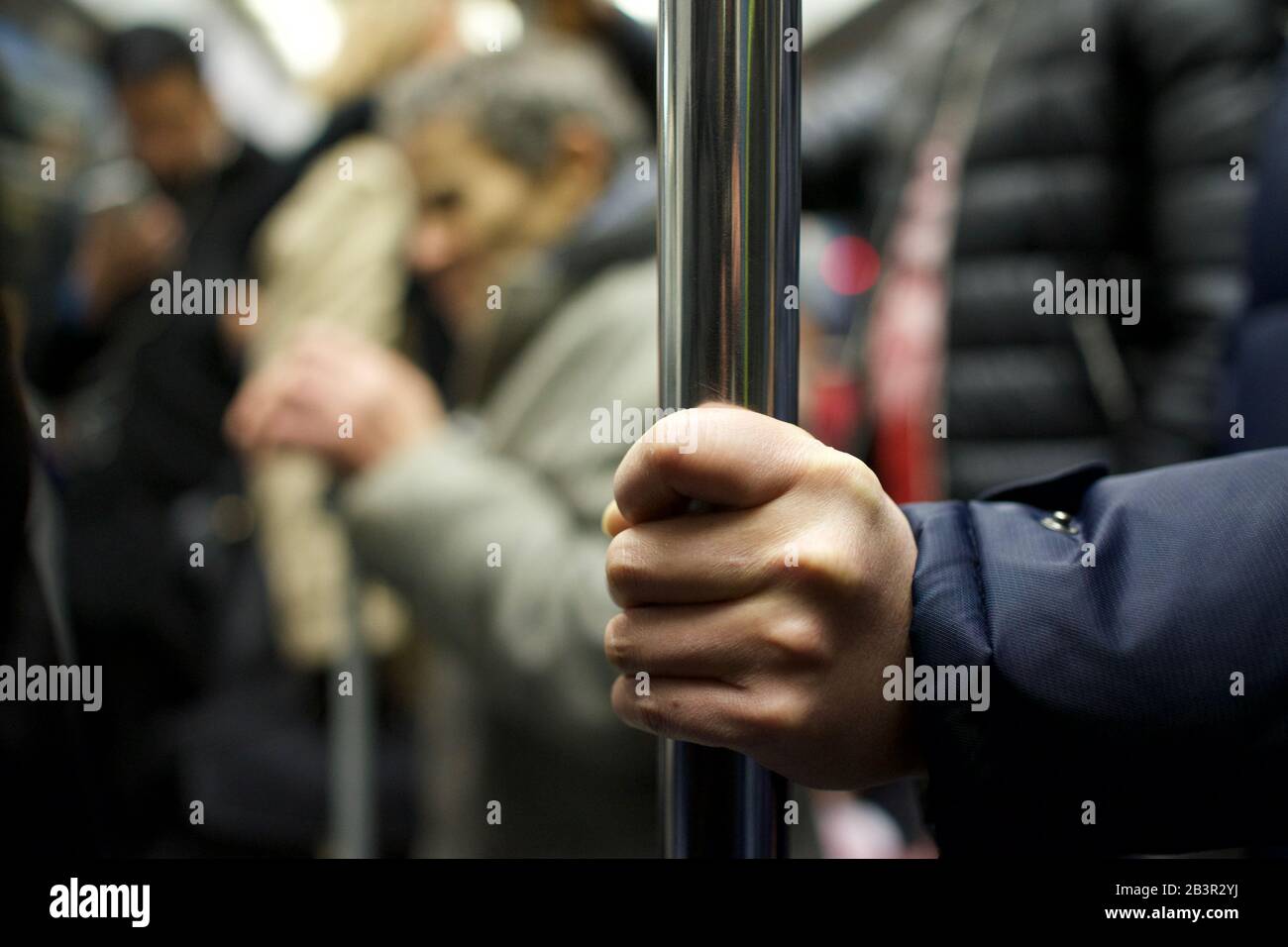 Man's hand holding handrail in train Stock Photo