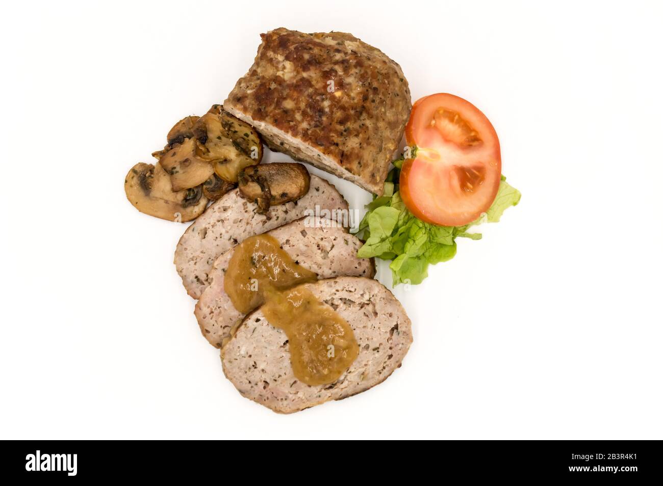 Meatloaf cut into slices with mushrooms, tomato and salad top view on an isolated white background. Stock Photo