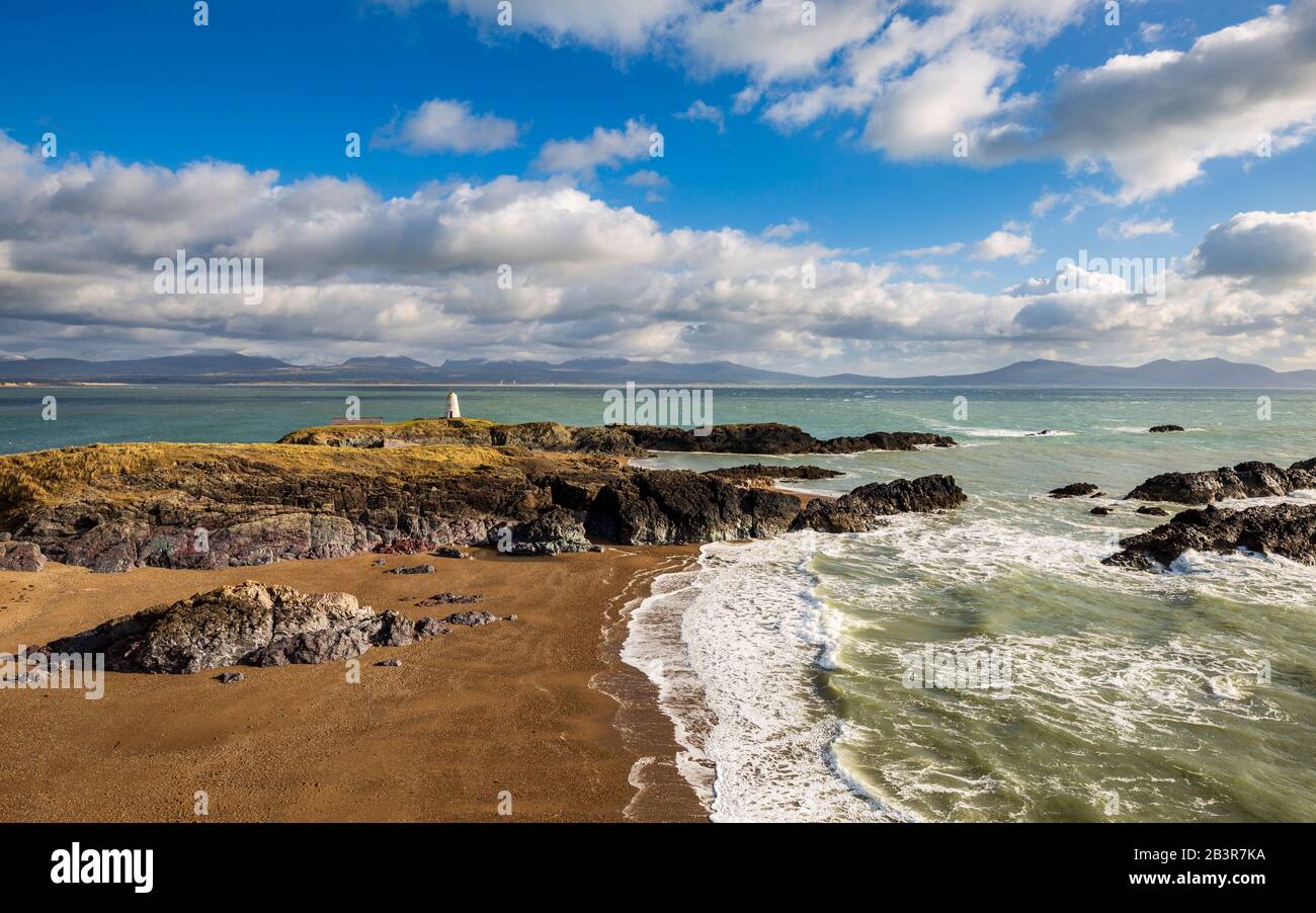 A view of Twr Bach and the snow capped Snowdonia mountains across Porth Twr Mawr on Llanddwyn island, Anglesey Stock Photo