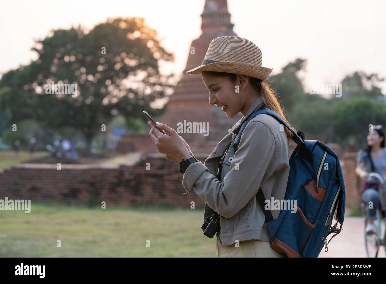 An Asian young woman checking on mobile phone while traveling in the ancient city. Stock Photo
