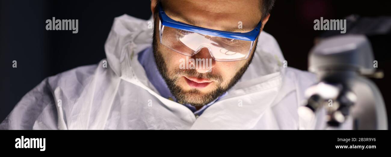 Man laboratory repairs instrument near microscope Stock Photo