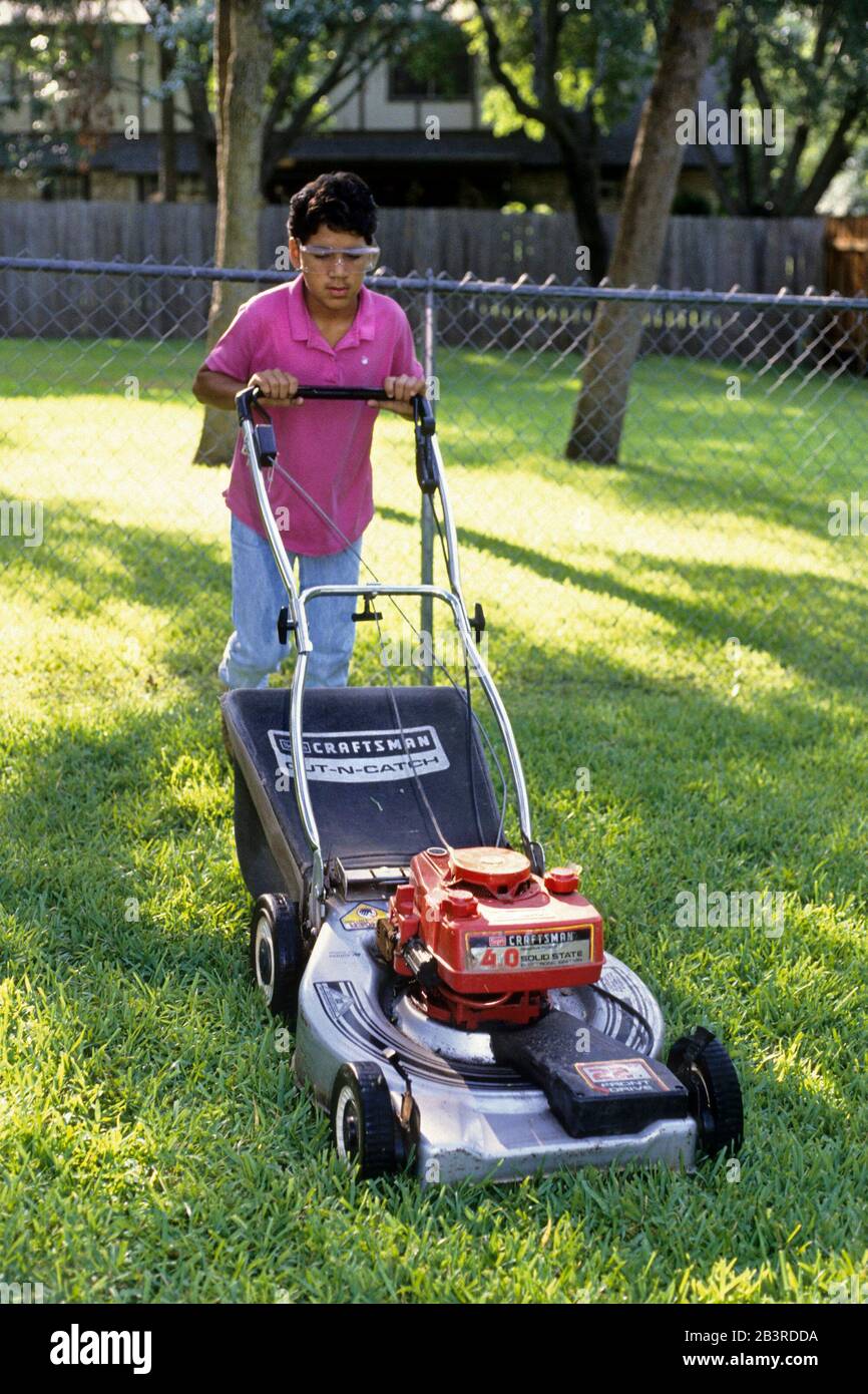 Austin Texas USA,1989: Hispanic boy, 13, mowing lawns for a summer job. MR XRE-0189   ©Bob Daemmrich Stock Photo