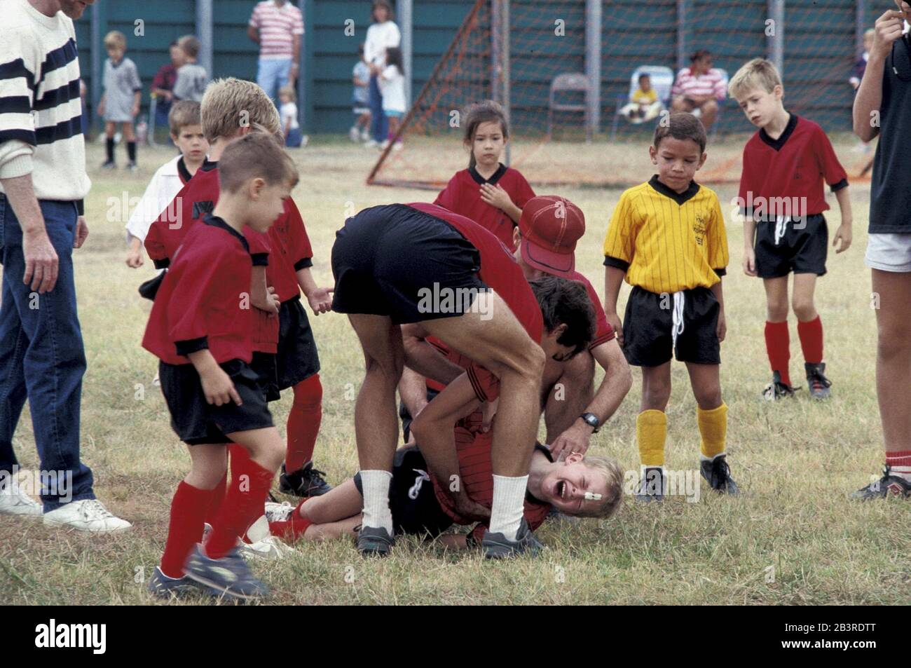 Austin, Texas USA, circa 1992: Seven- and eight-year-old soccer players show their concern as coaches attend to a crying injured teammate during youth league game.  ©Bob Daemmrich Stock Photo