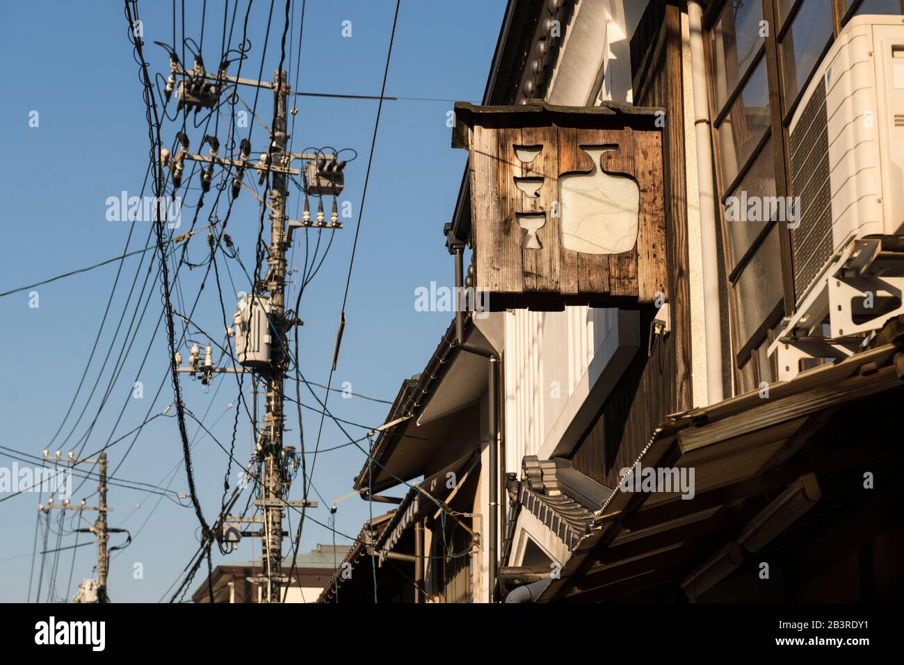 Street view with overhead power cables and wooden bar sign on Miyajima island, just outside Hiroshima, Japan Stock Photo