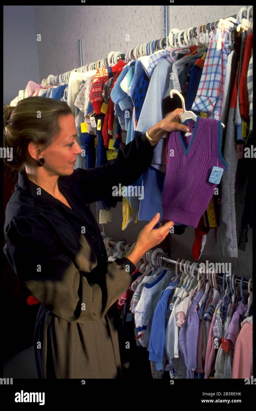 Austin Texas USA, circa 1989: Owner of children's clothing consignment shop looks over her merchandise. ©Bob Daemmrich Stock Photo