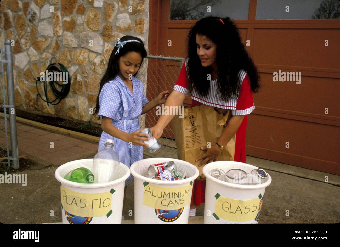 Austin Texas USA: Hispanic mother and daughter sort household trash into bins for plastic, aluminum and glass recycling. ©Bob Daemmrich Stock Photo