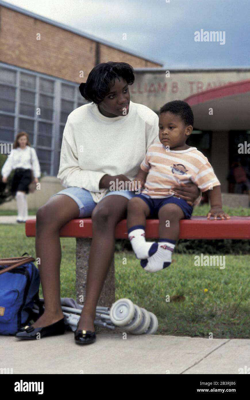 Austin, Texas USA, circa 1990: Teen mom with baby waiting for school bus at Travis High. The school has a nursery for its students who have young children. ©Bob Daemmrich Stock Photo