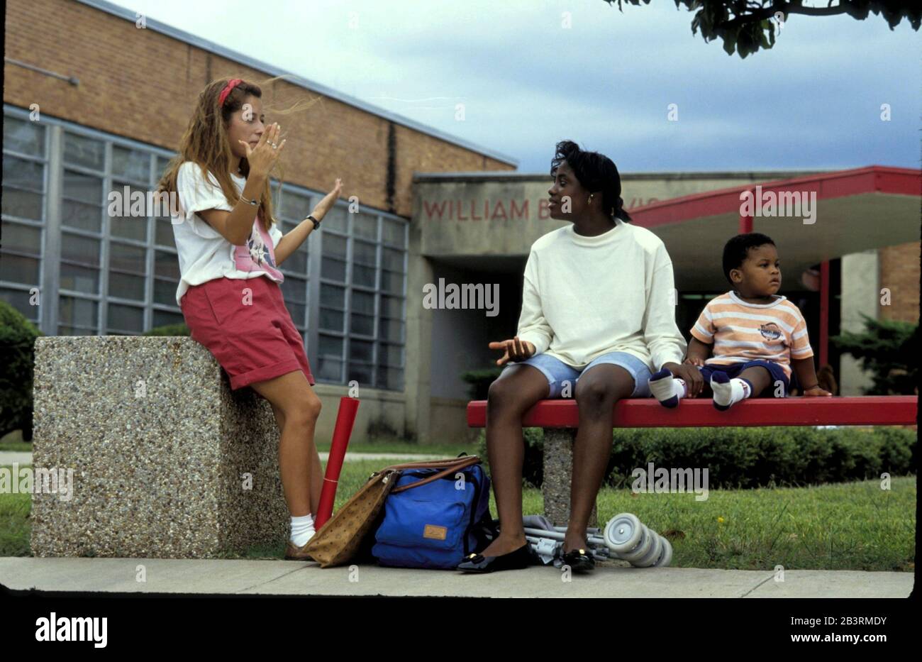 Austin, Texas USA, circa 1990: Teen mom with baby talks to classmate while waiting for school bus at Travis High. The school has a nursery for its students who have young children. ©Bob Daemmrich Stock Photo
