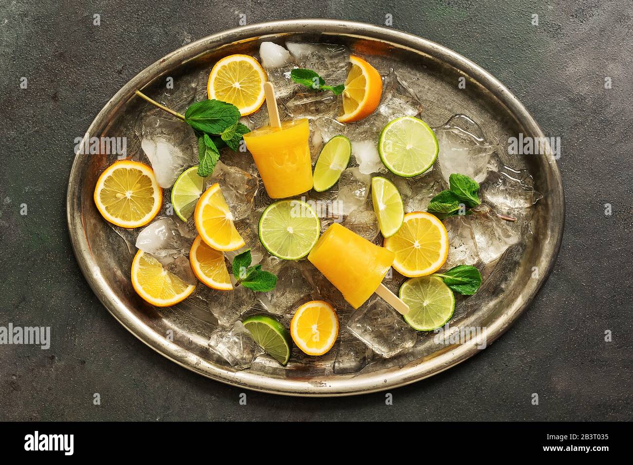 Frozen orange juice on a stick. Orange popsicles on a metal tray with
