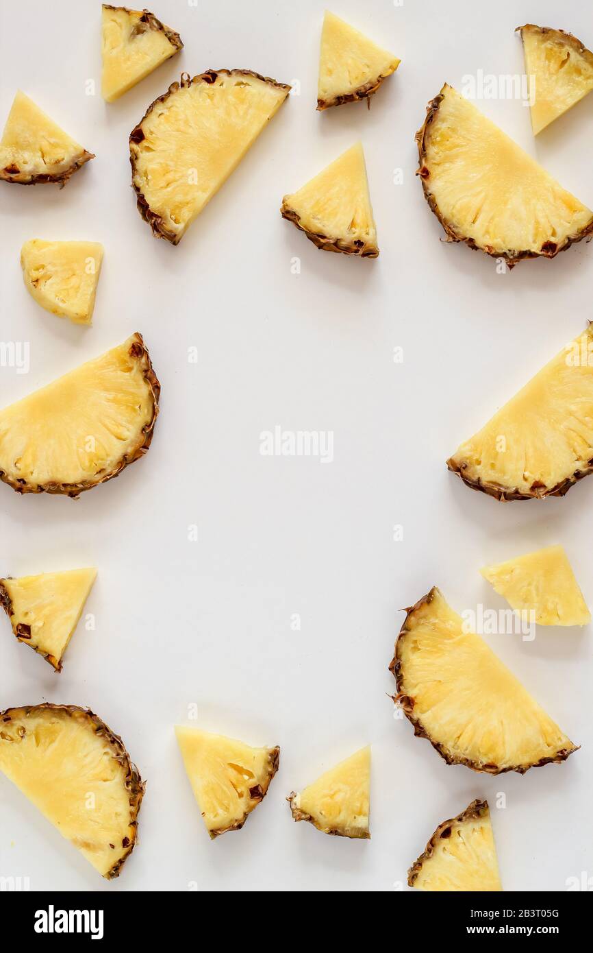 Bright flat lay with pineapple slices on a white background and a copy space in the middle Stock Photo