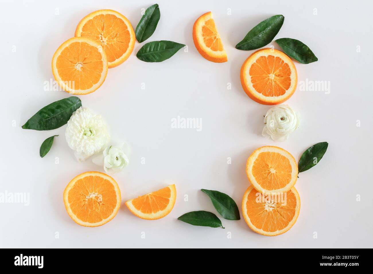 A frame made of orange slices, leaves and blooms on a white background with a copy space Stock Photo