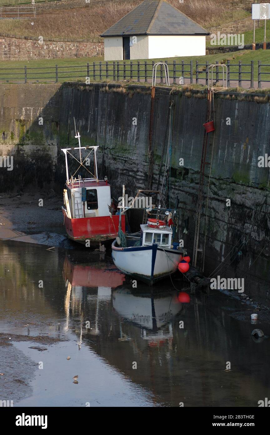 Vertical photo of fishing boats in harbour at low tide. Low tide in ...