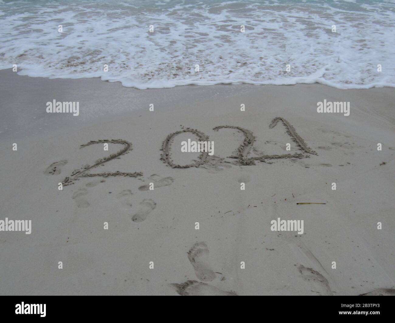 Happy New Year 2021, lettering on the beach with wave and clear blue