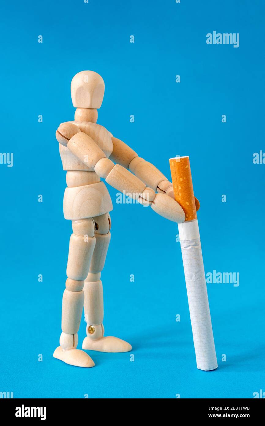 Wooden dool holding a cigarette. Concept of unhealthy habits. Stock Photo