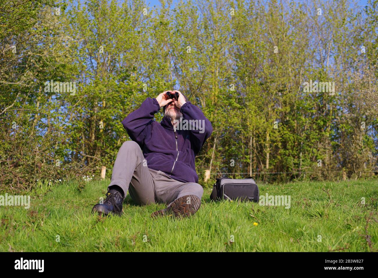 60 Year Old Man, Birdwatching with Binoculars on a Sunny Spring Day