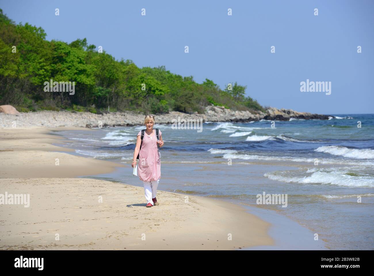 A woman walking on a sandy beach, Skane, Sweden Stock Photo
