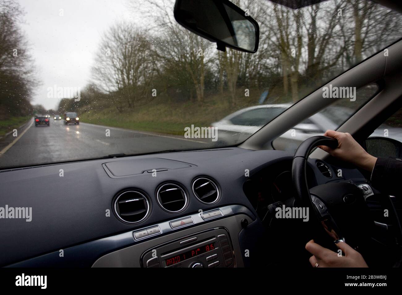 Woman driving on wet roads in the uk Stock Photo
