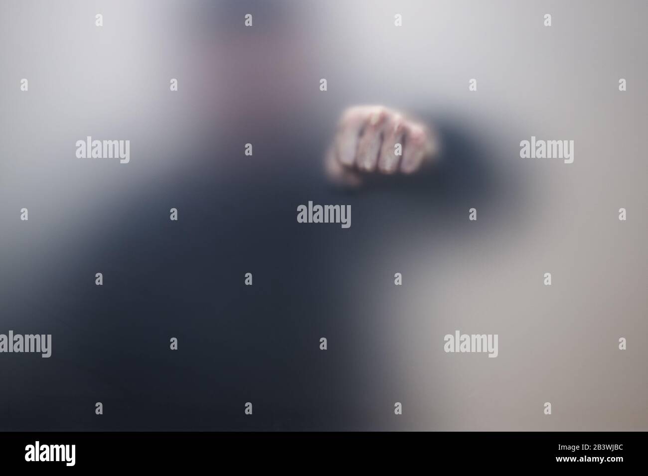 Male fist behind matte glass wall, abstract photo Stock Photo