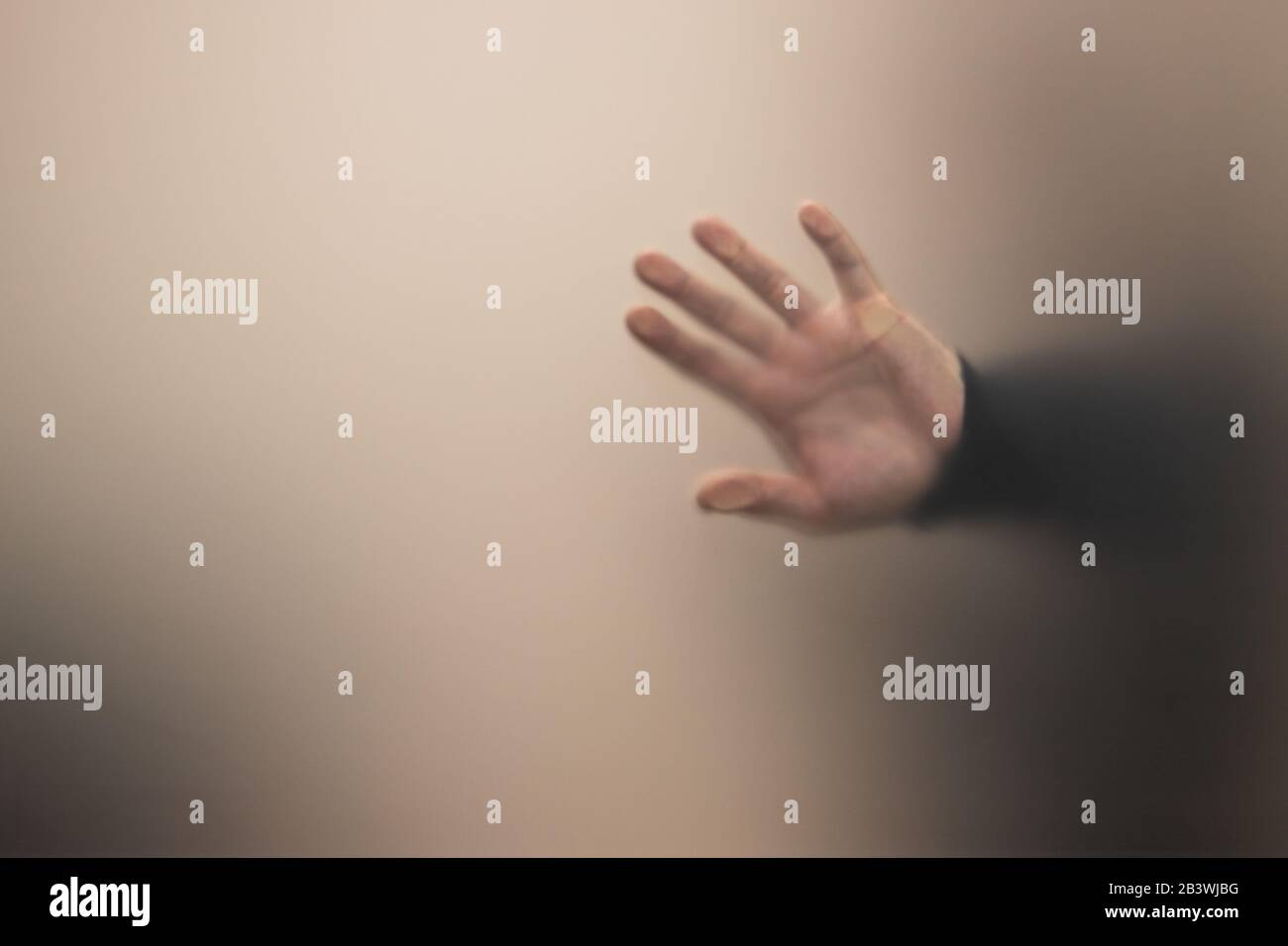 Blurred male hand behind gray matte glass wall, abstract unfocused photo background Stock Photo