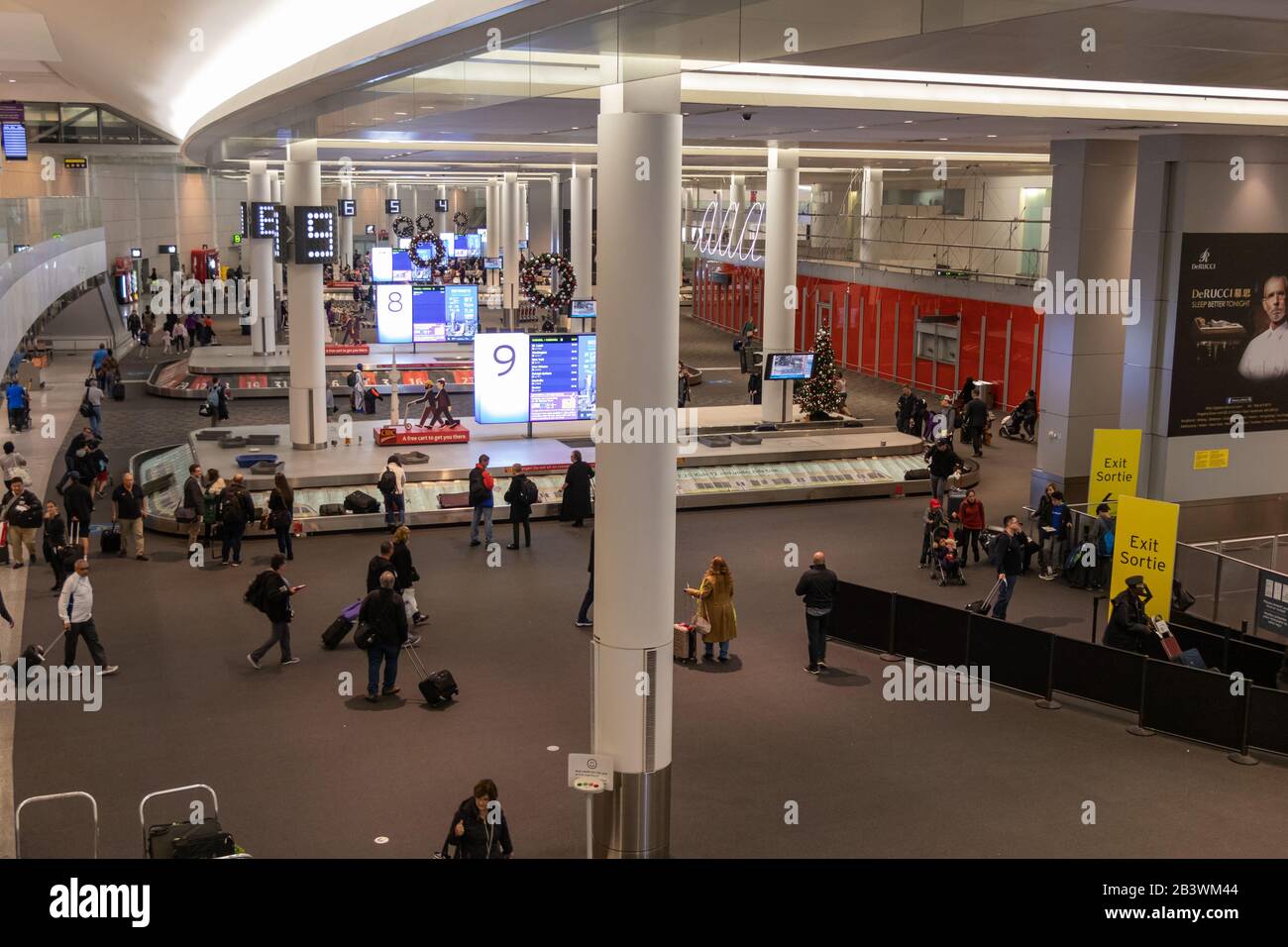 Passengers at baggage claim carousels inside Toronto Pearson Intl. Airport during the Christmas season. Stock Photo