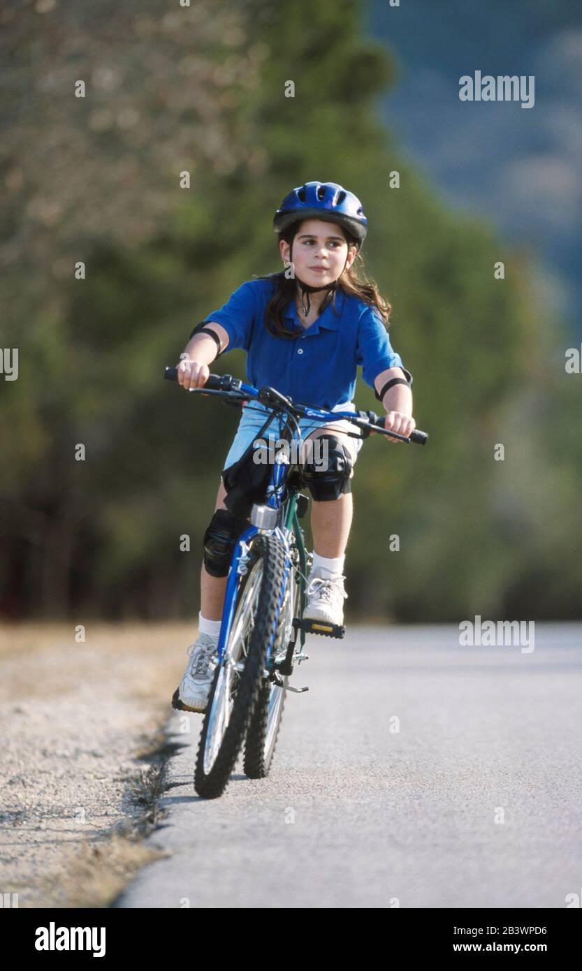 Austin Texas USA, 1998: Nine-year-old Panamanian-American girl safely enjoying bike ride on hilly residential street. ©Bob Daemmrich Stock Photo
