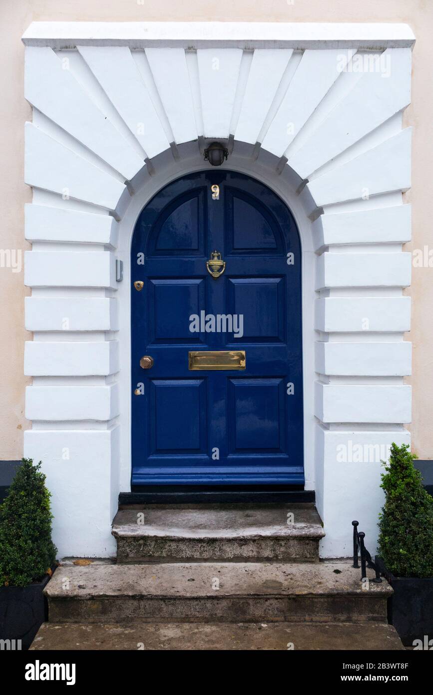 Bright or deep blue front door with brass door furniture and a stone