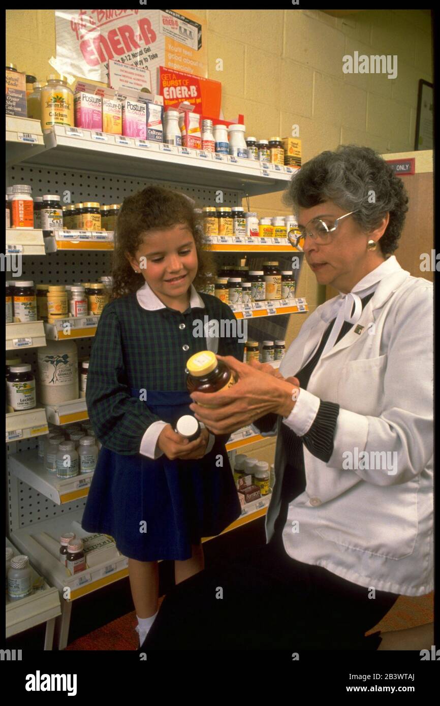 Austin Texas USA: Hispanic female pharmacist shows bottles of vitamins to little girl.  ©Bob Daemmrich Stock Photo
